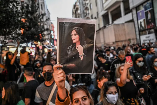 A protester holds a portrait of Mahsa Amini during a demonstration in support of Amini, a young Iranian woman who died after being arrested in Tehran by the Islamic Republic's morality police, on Istiklal avenue in Istanbul on September 20, 2022. Amini, 22, was on a visit with her family to the Iranian capital when she was detained on September 13 by the police unit responsible for enforcing Iran's strict dress code for women, including the wearing of the headscarf in public. She was declared dead on September 16 by state television after having spent three days in a coma. (Photo by Ozan Köse/AFP Photo)