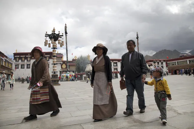 In this Friday, September 18, 2015 photo, a Tibetan family walks across Jokhang Square in the center of Lhasa, capital of the Tibet Autonomous Region in China. Chinese officials have taken foreign journalists on a visit to the region, normally off-limits to them, weeks after Communist Party officials commemorated the 50th anniversary of the establishment of the Tibet Autonomous Region. (Photo by Aritz Parra/AP Photo)