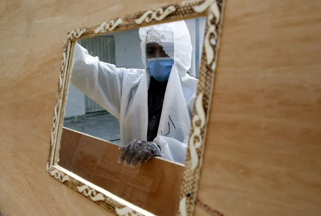 A worker wearing a face mask and a protective suit prepares coffins that are later distributed to hospitals to transport people who have died with the SARS-CoV-2 coronavirus that causes the pandemic COVID-19 disease in Islamabad, Pakistan, 07 June 2020. (Photo by Sohail Shahzad/EPA/EFE)