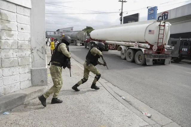 Police officers protect fuel trucks filled with gas as they drive from the Varreux fuel terminal, in Port-au-Prince, Haiti, Tuesday, November 8, 2022. Trucks lined up at the fuel terminal to fill up their tanks for the first time since a powerful gang seized control of the area nearly two months ago. Government officials said on Tuesday that gas stations, which have remained closed since mid-September, would be resupplied from Wednesday through Friday and would open to customers on Saturday. (Photo by Joseph Odelyn/AP Photo)