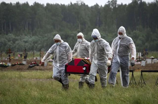 Cemetery workers wearing protective suits carry the coffin of a COVID-19 victim in the special purpose for coronavirus victims section of a cemetery in Kolpino, outside St.Petersburg, Russia, Tuesday, June 30, 2020. (Photo by Dmitri Lovetsky/AP Photo)