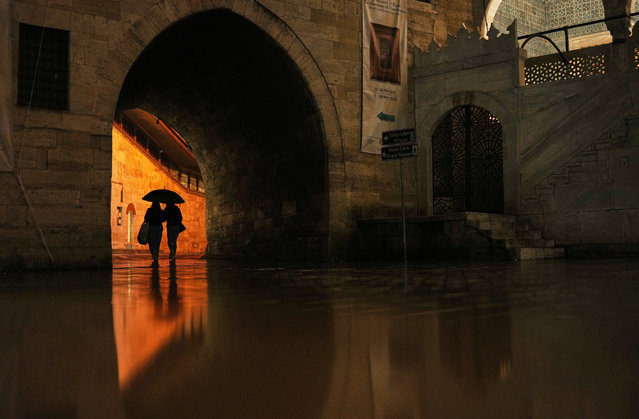 Passersby shelter against the rain with an umbrella next to Yeni Camii or New Mosque, in Istanbul, Turkey, Friday, March 28, 2025. (Photo by Francisco Seco/AP Photo)