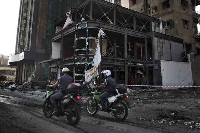 Police officers pass a damaged building near the scene of an explosion that hit the seaport of Beirut, Lebanon, Wednesday, August 5, 2020. A massive explosion rocked Beirut on Tuesday, flattening much of the city's port, damaging buildings across the capital and sending a giant mushroom cloud into the sky. (Photo by Bilal Hussein/AP Photo)
