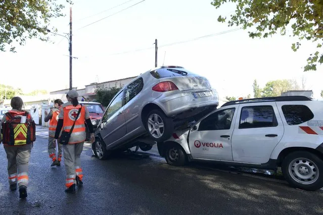 French Red Cross volunteers walk past an upended car on a street after flooding caused by torrential rain in Biot, France, October 4, 2015. (Photo by Jean-Pierre Amet/Reuters)
