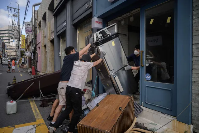 Store workers clean up damage to a shop caused by typhoon Maysak in Busan on September 3, 2020. At least one person was killed and more than 2,000 people evacuated to temporary shelters in South Korea as a powerful typhoon churned across the peninsula, authorities said. (Photo by Ed Jones/AFP Photo)