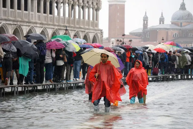 Poeple wade through the high water in Venice, Italy, 14 October 2015. Venice saw its first 'acqua alta' of the year with water 105 cm above sea level causing low-lying areas of the lagoon city to be flooded. An acqua alta is a natural phenomenon and occurrs when especially high tides caused by the moon's gravitational pull coincide with a strong scirocco that forces water from the Adriatic into the Venetian lagoon. (Photo by Andrea Merola/EPA)