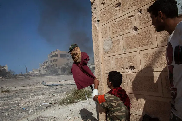 A fighter, supporter of the Libyan Government of National Accord, uses a dummy to catch the attention of Islamic State group snipers at the frontline in Sirte on September 22, 2016. Ten jihadists and nine pro-government fighters died in clashes around the last positions of the Islamic State group in the Libyan coastal city of Sirte, 450 kilometres (280 miles) east of the Libyan capital Tripoli, medical and military sources said. (Photo by Fabio Bucciarelli/AFP Photo)