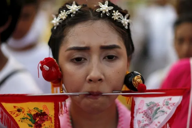 A devotee of the Chinese Jui Tui shrine walks with spikes pierced through her cheeks during a procession celebrating the annual vegetarian festival in Phuket, Thailand October 19, 2015. (Photo by Jorge Silva/Reuters)