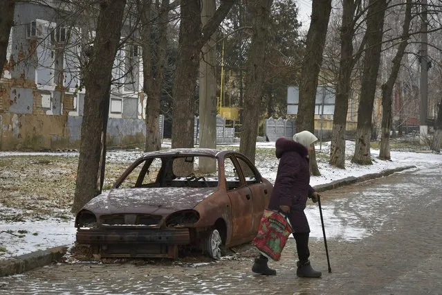 A local resident walks past a burnt car that was damaged in Russian shelling in the town of Orekhovo, Zaporizhzhya region, Ukraine, Monday, January 30, 2023. (Photo by Andriy Andriyenko/AP Photo)