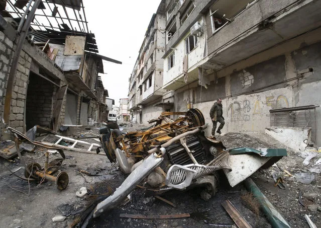 A man walks in the yard of an apartment building damaged by shelling by Azerbaijan's artillery during a military conflict in Stepanakert, self-proclaimed Republic of Nagorno-Karabakh, Wednesday, October 7, 2020. Armenia accused Azerbaijan of firing missiles into the capital of the separatist territory of Nagorno-Karabakh, while Azerbaijan said several of its towns and its second-largest city were attacked. (Photo by Dmitri Lovetsky/AP Photo)