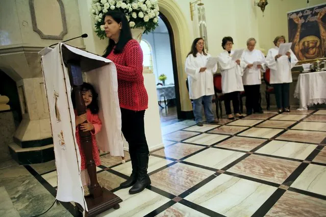A woman reads the Bible from the pulpit as a girl hides underneath during a mass at Sao Francisco de Assis (Saint Francis of Assis) Church in Sao Paulo October 4, 2015. (Photo by Nacho Doce/Reuters)