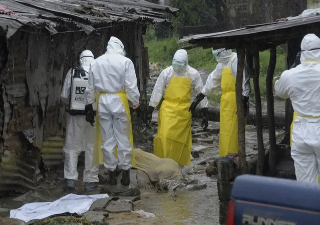 Health workers wearing protective clothing prepare to carry an abandoned dead body presenting with Ebola symptoms at Duwala market in Monrovia, Liberia, in this August 17, 2014 file photo. (Photo by Reuters/2Tango)