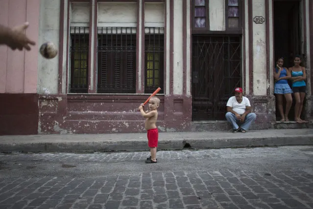 Carlos Ortega Ponce, 3, plays baseball with his father in front of his home in Havana, October 16, 2014. (Photo by Alexandre Meneghini/Reuters)