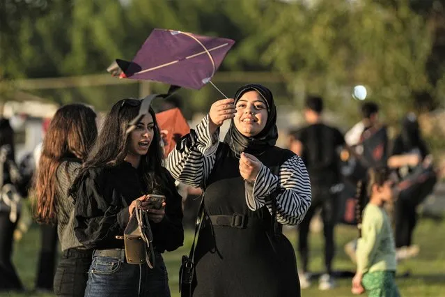A woman launches a Kite during Baghdad Kite Festival in Baghdad, Iraq, Friday, March 17, 2023. (Photo by Hadi Mizban/AP Photo)
