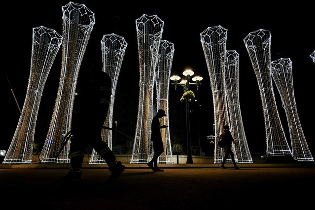 People walk past a Christmas decoration in downtown Caracas on October 1, 2025. (Photo by Federico Parra/AFP Photo)