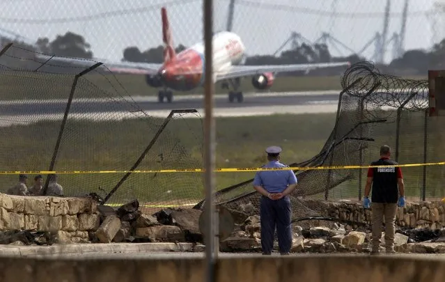 Investigators and rescue services at the scene of a plane crash at the airport in Valletta, Malta, 24 October 2016. A small aircraft conducting a surveillance mission over the Mediterranean for France's defense ministry crashed on take-off in Malta on Monday, killing all five people on board. (Photo by Darrin Zammit Lupi/Reuters)