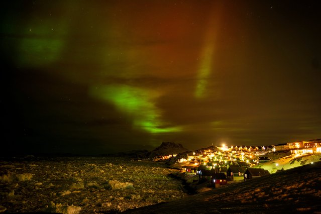 The northern lights appear over homes in Nuuk, Greenland, early morning Thursday, February 20, 2025. (Photo by Emilio Morenatti/AP Photo)