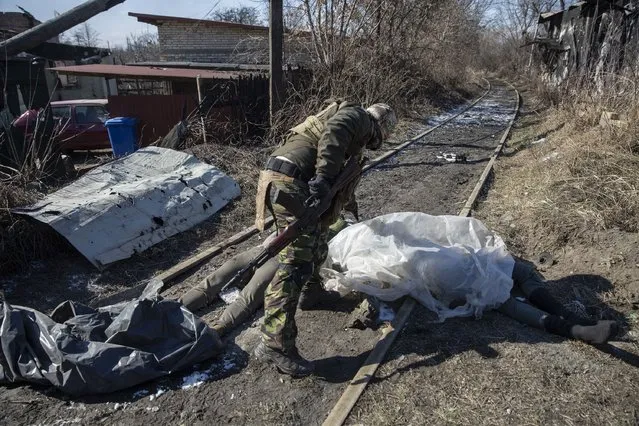 A member of the Ukrainian Territorial Defense Force by the bodies of two Russian soldiers in Irpin, Ukraine on March 10,2022. (Photo by Heidi Levine for The Washington Post)
