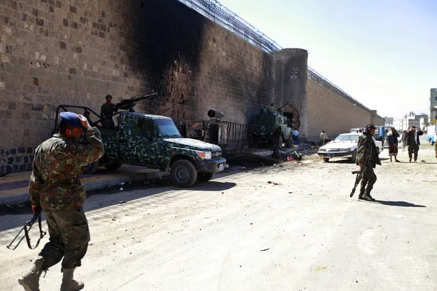 Policemen stand guard next to a wall of the central prison in Sanaa after a bomb exploded outside, February 14, 2014. (Photo by Mohamed al-Sayaghi/Reuters)