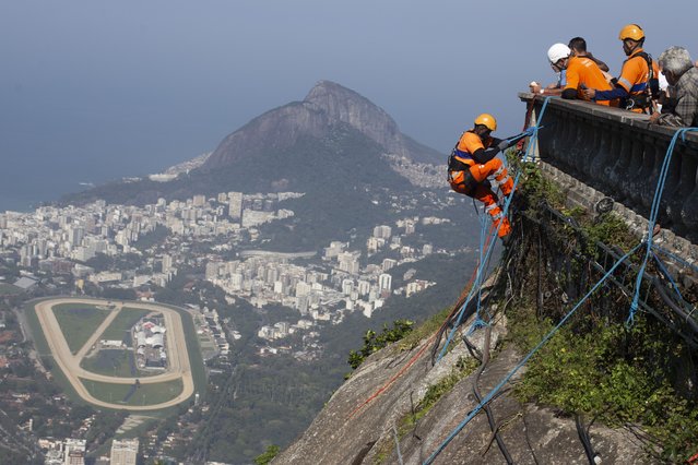 Trash collectors rappel down Corcovado Mountain to remove garbage dumped on the slope of the Christ the Redeemer Statue in Rio de Janeiro, Thursday, August 22, 2024. (Phoot by Bruna Prado/AP Photo)