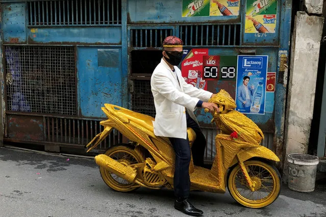 A man rides a golden motorbike on a street in Bangkok, Thailand on August 14, 2020. (Photo by Jorge Silva/Reuters)