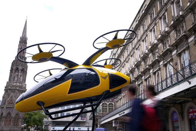 Pedestrians pass a prototype of a flying taxi, which is currently in development in the United Arab Emirates (UAE), after it was unveiled in the taxi rank outside Charing Cross railway station in London, Wednesday, October 9, 2024. (Photo by Kirsty Wigglesworth/AP Photo)