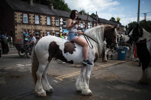A woman checks her phone as she rides a horse on The Sands street on the opening day of the annual Appleby Horse Fair, in the town of Appleby- in- Westmorland, north- west England on June 7, 2018. The annual event attracts thousands of travellers from across Britain to gather and buy and sell horses. (Photo by Oli Scarff/AFP Photo)