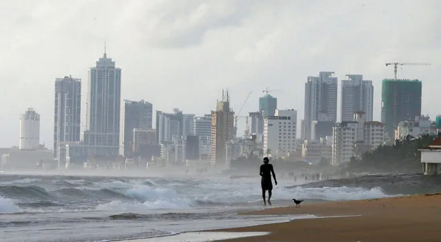 A man walks along a beach, against the backdrop of Colombia's Financial City, Sri Lanka June 12, 2018. (Photo by Dinuka Liyanawatte/Reuters)