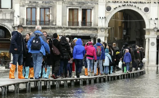 Tourists walk on raised platforms above flood waters during a period of seasonal high water and on the first day of carnival, in Venice February 1, 2015. (Photo by Stefano Rellandini/Reuters)