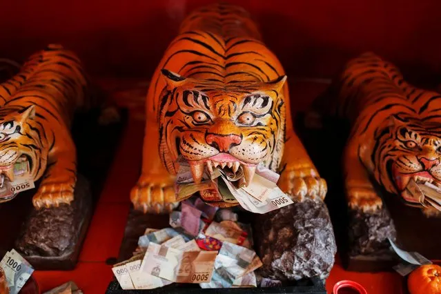 Banknotes are stuffed into tiger sculptures at Dharma Bhakti temple during Lunar New Year celebrations in Jakarta, Indonesia, February 12, 2021. (Photo by Willy Kurniawan/Reuters)