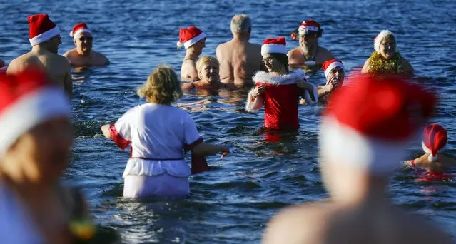 Members of the ice swimming club “Berliner Seehunde” (Berlin Seals) take a dip in the Orankesee lake as part of their traditional Christmas swimming session in Berlin, Germany, December 25, 2015. (Photo by Hannibal Hanschke/Reuters)