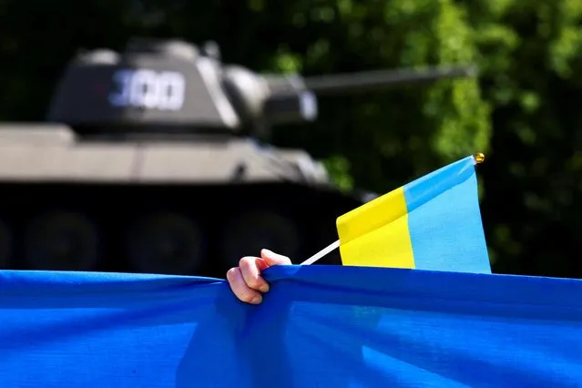 A person holds a Ukrainian flag during a wreath-laying ceremony organized by the Ukrainian Embassy to mark Victory Day and the 77th anniversary of the end of World War Two, at the Soviet War Memorial at Tiergarten Park in Berlin, Germany on May 8, 2022. (Photo by Christian Mang/Reuters)