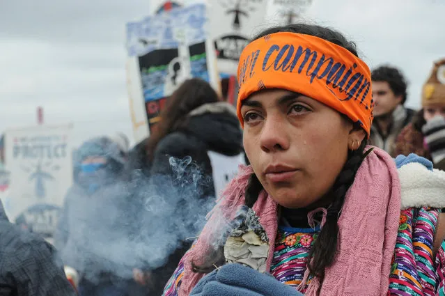 A protester cries while watching a demonstration on Turtle Island on Thanksgiving day during a protest against plans to pass the Dakota Access pipeline near the Standing Rock Indian Reservation, near Cannon Ball, North Dakota, U.S. November 24, 2016. (Photo by Stephanie Keith/Reuters)