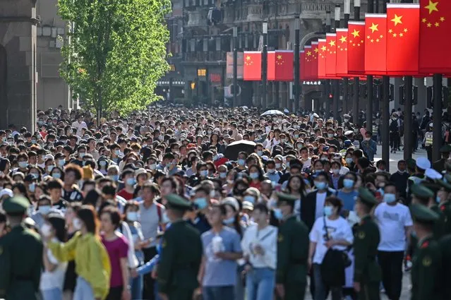 People walk along a pedestrian street during a labour day holiday in Shanghai on May 1, 2021. (Photo by Hector Retamal/AFP Photo)