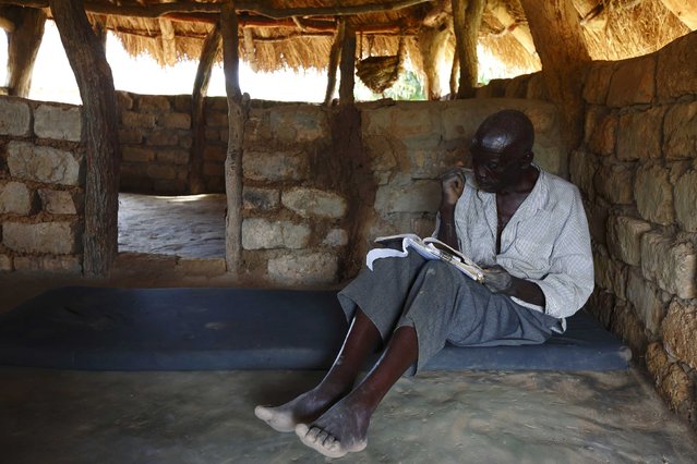 HIV-positive 71-year-old Sylverio Hachiploa reads in his thatched hut during a visit by a home-based care team in the village of Nedwmba, south of the Chikuni Mission in the south of Zambia February 23, 2015. (Photo by Darrin Zammit Lupi/Reuters)