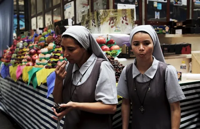 Nuns eat grapes after buying fruit at the Municipal Market in Sao Paulo, Brazil, January 7, 2016. (Photo by Nacho Doce/Reuters)