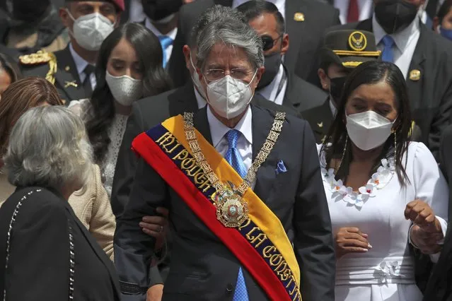 Ecuador's new President Guillermo Lasso wears the presidential sash after his inauguration ceremony as he exits the National Assembly with his wife Maria de Lourdes, partially covered left, and daughter Maria Mercedes, second from left, in Quito, Ecuador, Monday, May 24, 2021. At right is National Assembly President Guadalupe Llora. (Photo by Dolores Ochoa/AP Photo)
