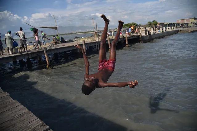 A boy jumps into the sea while playing with friends near Wharf Soleil in the Cite Soleil neighborhood of Port- au- Prince, Haiti, on August 28, 2018. (Photo by Hector Retamal/AFP Photo)