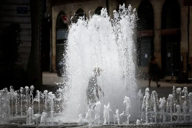 A child cools off in a public fountain during high temperatures in Nantes, France on August 23, 2023. (Photo by Stephane Mahe/Reuters)