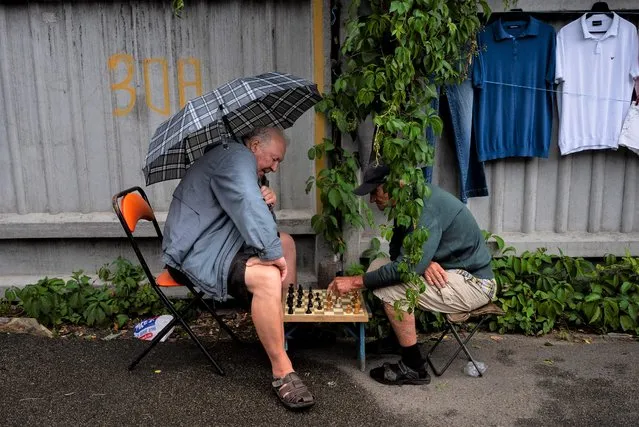 Two vendors play chess at a flea market in Kyiv, Ukraine, Saturday, July 8, 2023. The Pochaina neighborhood in the Ukrainian capital comes alive every weekend as hundreds of people flock to its famous flea market, looking for finds. (Photo by Jae C. Hong/AP Photo)