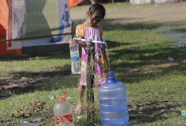A girl fills water jugs at a temporary shelter in Palu, Central Sulawesi Indonesia, Thursday, Octuber 4, 2018. Life is on hold for thousands living in tents and shelters in the Indonesian city hit by a powerful earthquake and tsunami, unsure when they'll be able to rebuild and spending hours each day often futilely trying to secure necessities such as fuel for generators. (Photo by Tatan Syuflana/AP Photo)