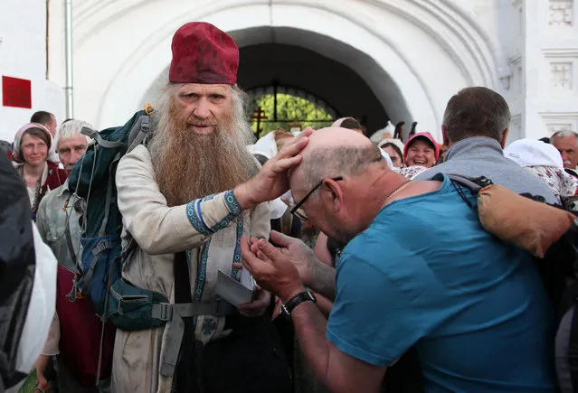 A Russian Orthodox priest blesses pilgrims during the Velikoretsky religious procession with a venerated wonderworking icon of St Nicholas in Kirov Region, Russia on June 5, 2021. (Photo by Dmitry Feoktistov/TASS)