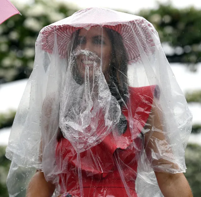 A racegoer arrives during pouring rain before the running of the Melbourne Cup at the Flemington Racecourse in Melbourne, Australia, Tuesday, November 6, 2018. (Photo by Andy Brownbill/AP Photo)