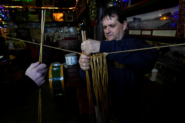 Chris Slattery assembles a straw costume during an Irish tradition of Hunting of the Wren festival held every St. Stephen's Day in Dingle, Ireland December 26, 2016. (Photo by Clodagh Kilcoyne/Reuters)