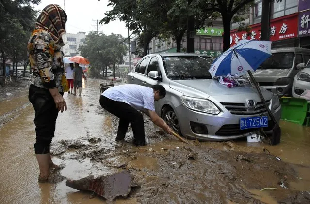 In this photo released by Xinhua News Agency, residents clean up the aftermath of a flood in Mihe Town of Gongyi City, in central China's Henan province on Wednesday, July 21, 2021. China's military has blasted a dam to release floodwaters threatening one of its most heavily populated provinces, as the death toll in widespread flooding rose to more than two dozens. (Photo by Han Chaoyang/Xinhua via AP Photo)