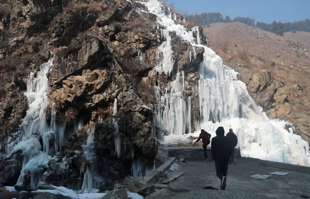 Kashmiri people walk near a frozen waterfall in the Tangmarg area of north Kashmir, some 30 kilometres from Srinagar the summer capital of Indian Kashmir, 27 December 2018. Kashmir valley is witnessing record-breaking cold this winter. The night of 27 December was the coldest night in 28 years at minus 7.6 degree Celsius. The local meteorological department has said that the ongoing cold conditions are expected to continue until New Year's Eve. (Photo by Farooq Khan/EPA/EFE)