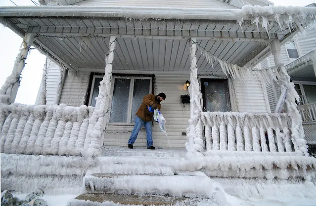 Stephen Sunder, a general contractor for First General Services of N.E.P.A. based in Wilkes-Barre, Pa., dumps rock salt to help melt thick layers of ice that cover a home on the 400 block of East Market Street in the Green Ridge Section of Scranton, Pa., Thursday, February 11, 2016, after a 12-inch water main broke. (Photo by Butch Comegys/The Times & Tribune via AP Photo)