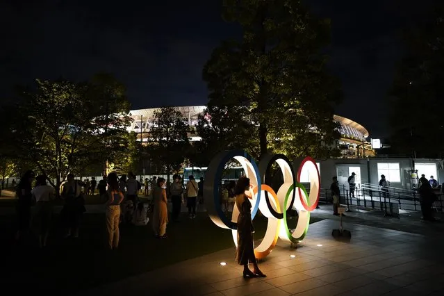 People take pictures with the Olympic rings outside the Olympic Stadium during the 2020 Summer Olympics, Saturday, July 31, 2021, in Tokyo, Japan. (Photo by Jae C. Hong/AP Photo)