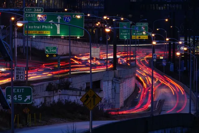 In this image made with a long exposure, motor vehicles move along Interstate 76 ahead of the Thanksgiving Day holiday in Philadelphia, Wednesday, November 22, 2023. (Photo by Matt Rourke/AP Photo)