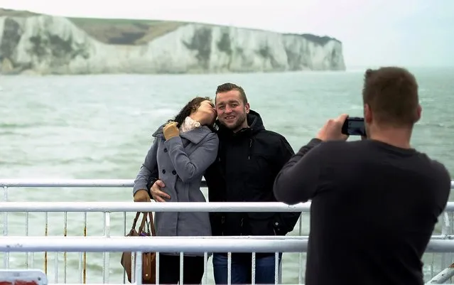 Tourists pose for a photograph in front of the White Cliffs of Dover, as they cross the Channel on a ferry, Britain February 20, 2016. Stand on top of the white cliffs of Dover on a clear day and you can see the French coast and the constant traffic of ferries crossing the Channel, binding Britain and Europe through the flow of people and goods. Seen through many British eyes, the famous cliffs conjure up a different vision, that of a fiercely independent island nation with a nearly thousand-year history of repelling would-be invaders from the continent just 33 km (21 miles) away. (Photo by Phil Noble/Reuters)